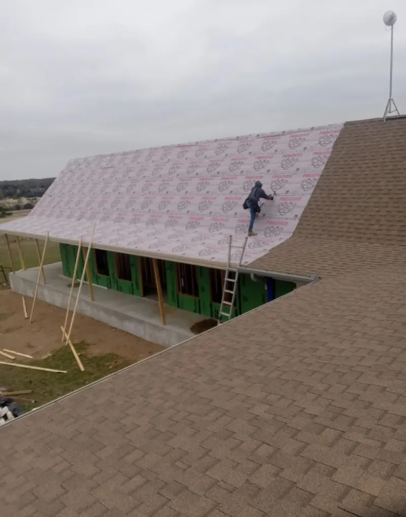 Worker preparing underlayment for a metal roof installation in Nibley